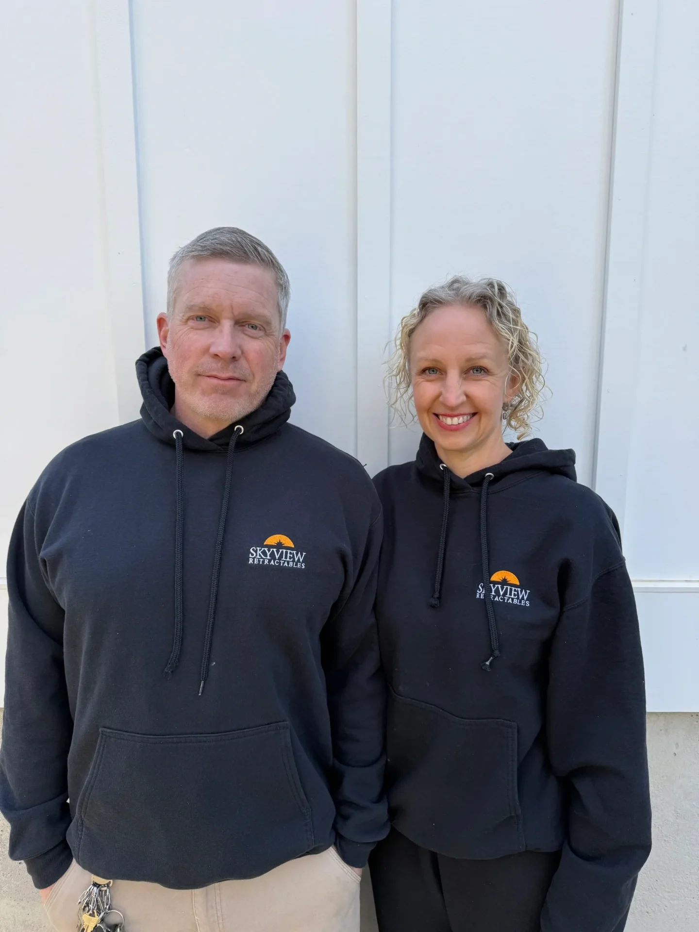 A man and a women standing wearing black hoodies